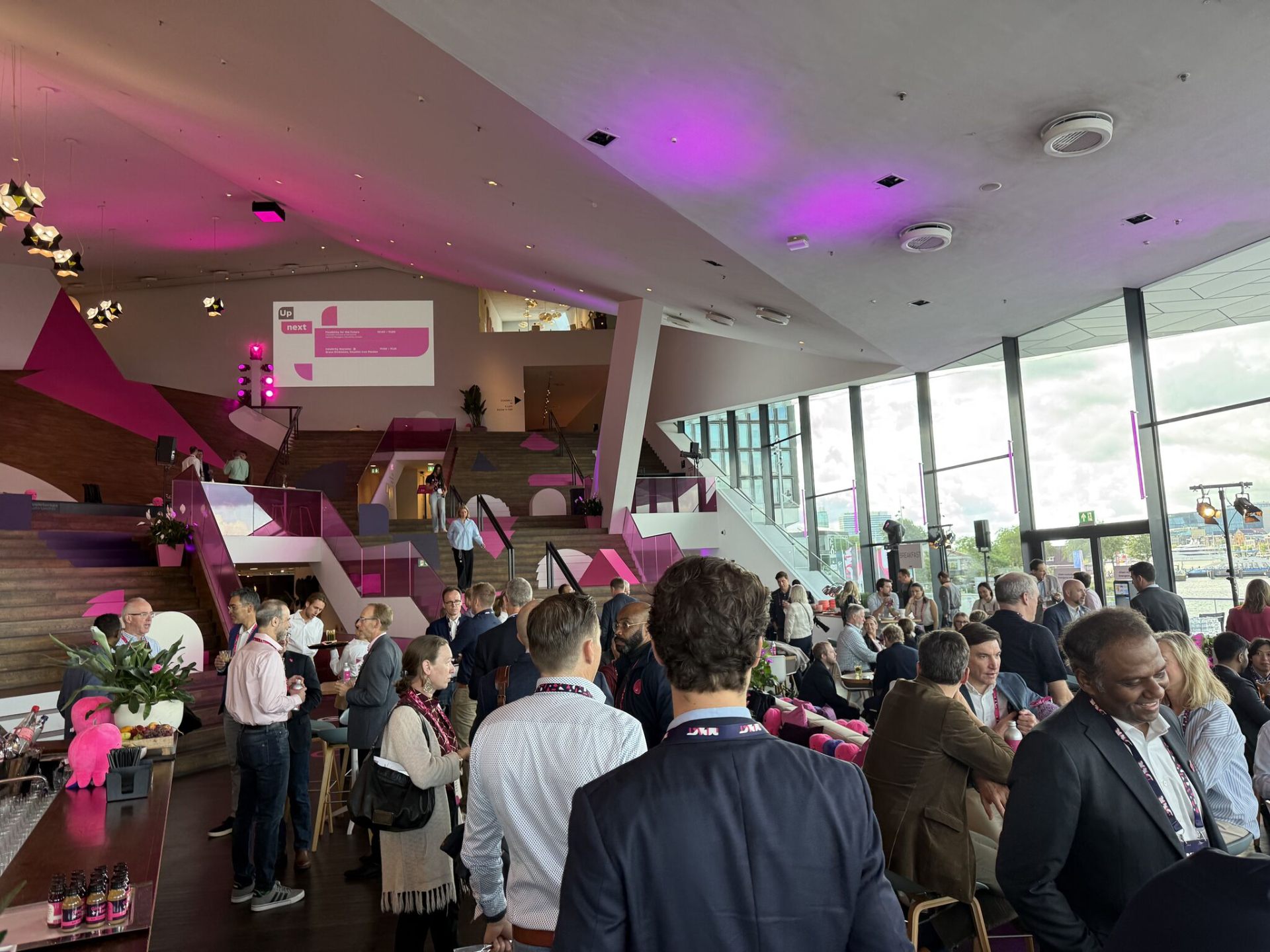 Delegates networking in the EyeFilm Museum foyer under pink Impact lighting